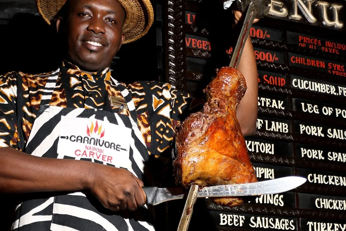 A Carnivore carver presenting a roast leg of meat on a Maasai sword