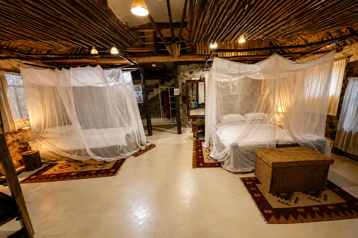 Twin beds under white mosquito netting inside a Mbweha Camp cottage
