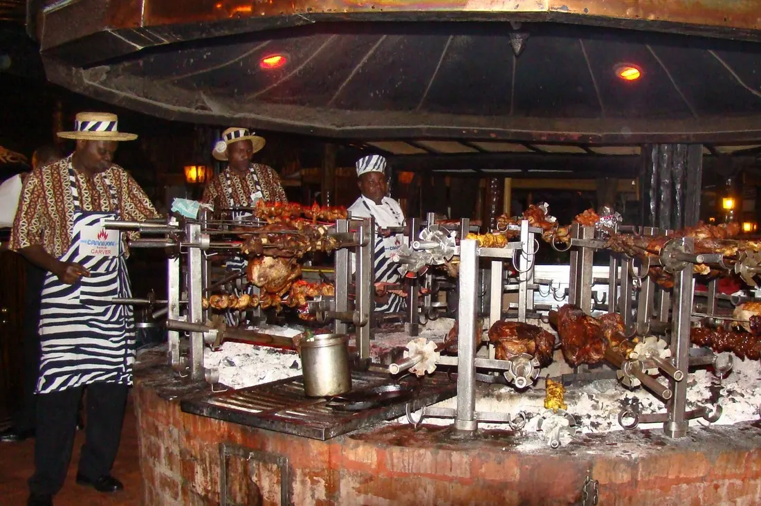 Chefs turning skewers of meat over the open fire at Carnivore