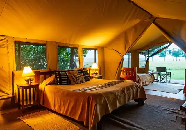 Luxury en-suite tent interior at Governors' Camp with lamplight and open plains view