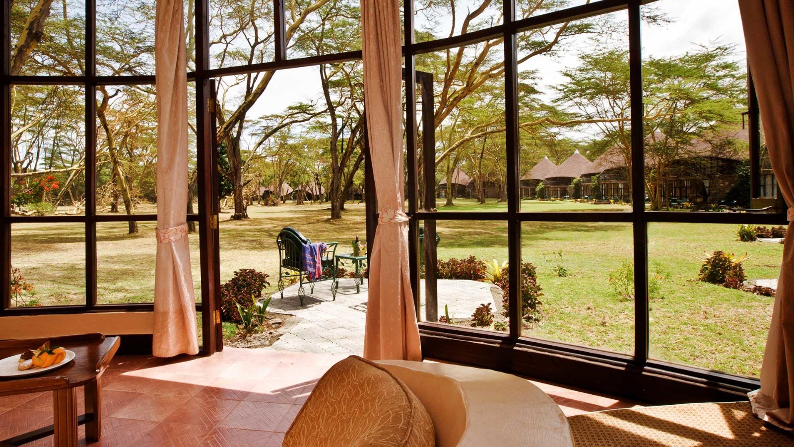 View through tall windows onto acacia lawns at Lake Naivasha Sopa Lodge