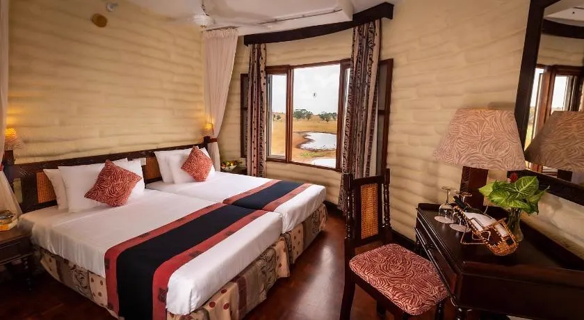 Guest room at Salt Lick Safari Lodge with twin beds and a window looking onto the waterhole
