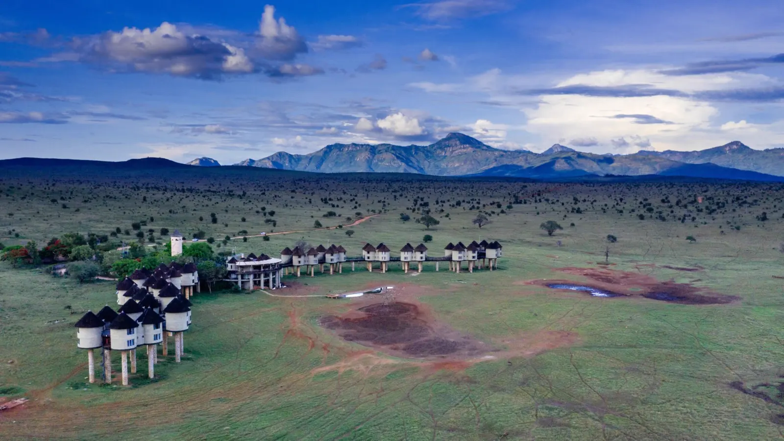 Aerial view of Salt Lick Safari Lodge with the Taita Hills rising behind green savannah