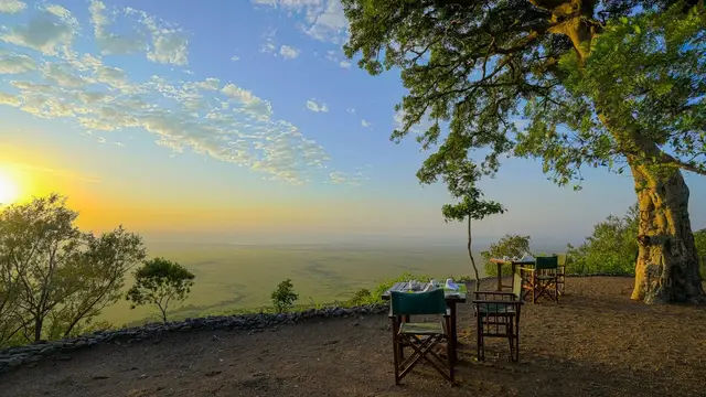 Breakfast tables set on an escarpment overlooking the Mara plains at sunrise