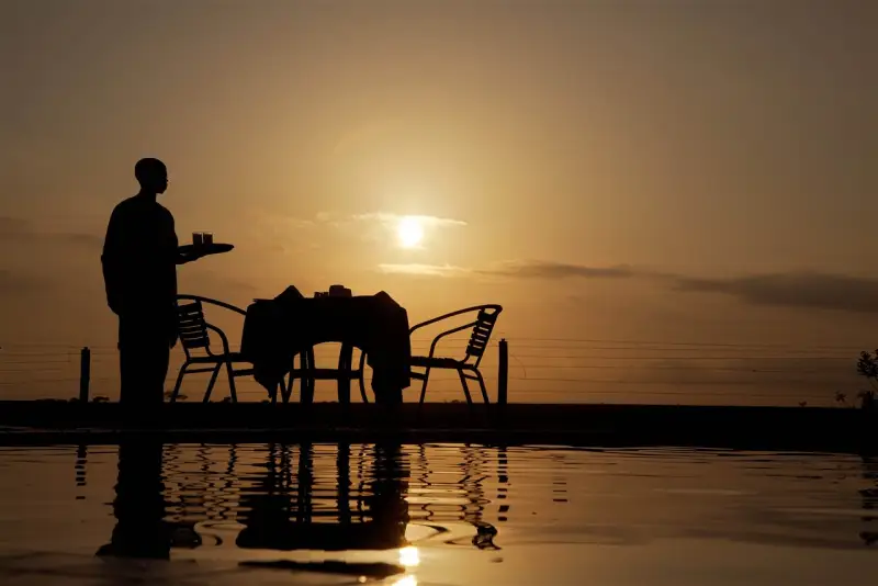 Waiter serving sundowners against a golden Tsavo sunset