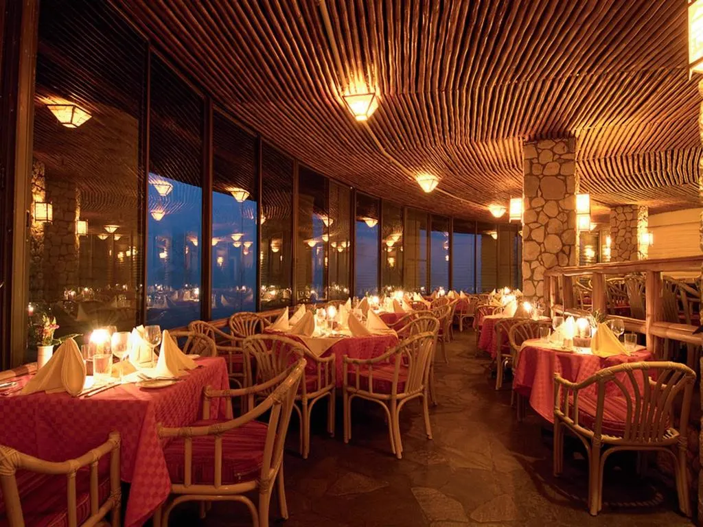 Warmly lit restaurant at Salt Lick Safari Lodge with candlelit tables under a thatched ceiling